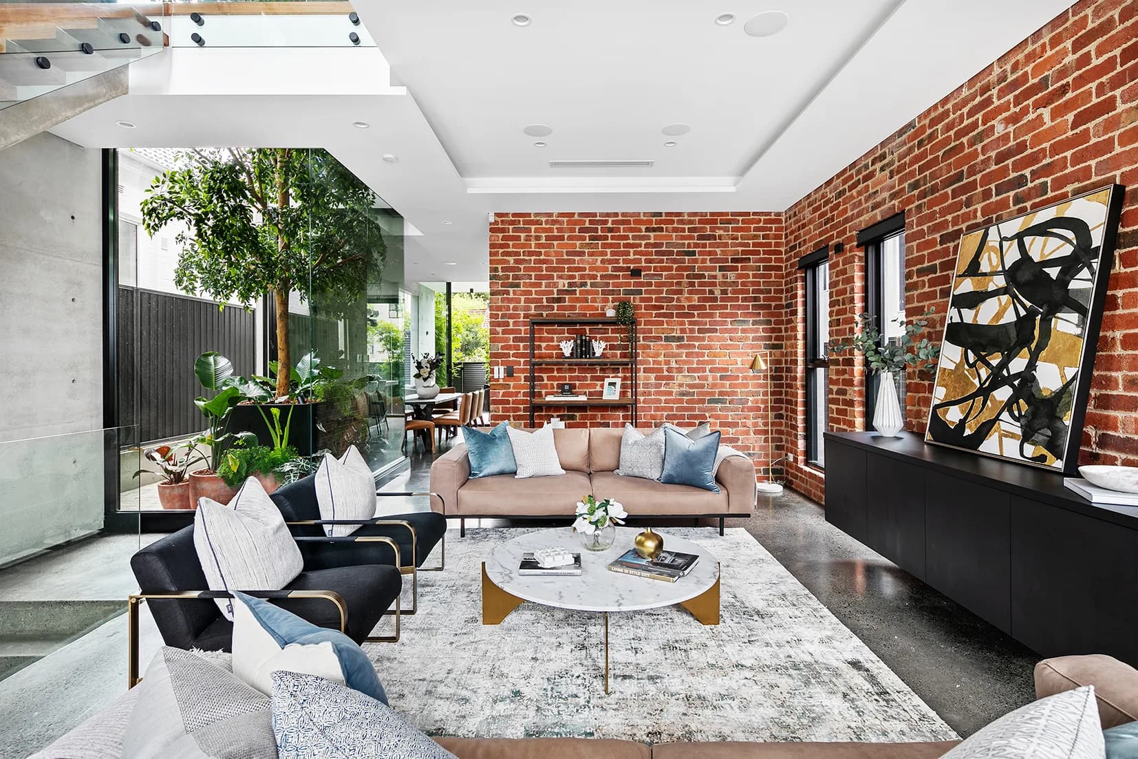 Living room at The Arc with a recycled brick feature wall, polished concrete floors and a skylight