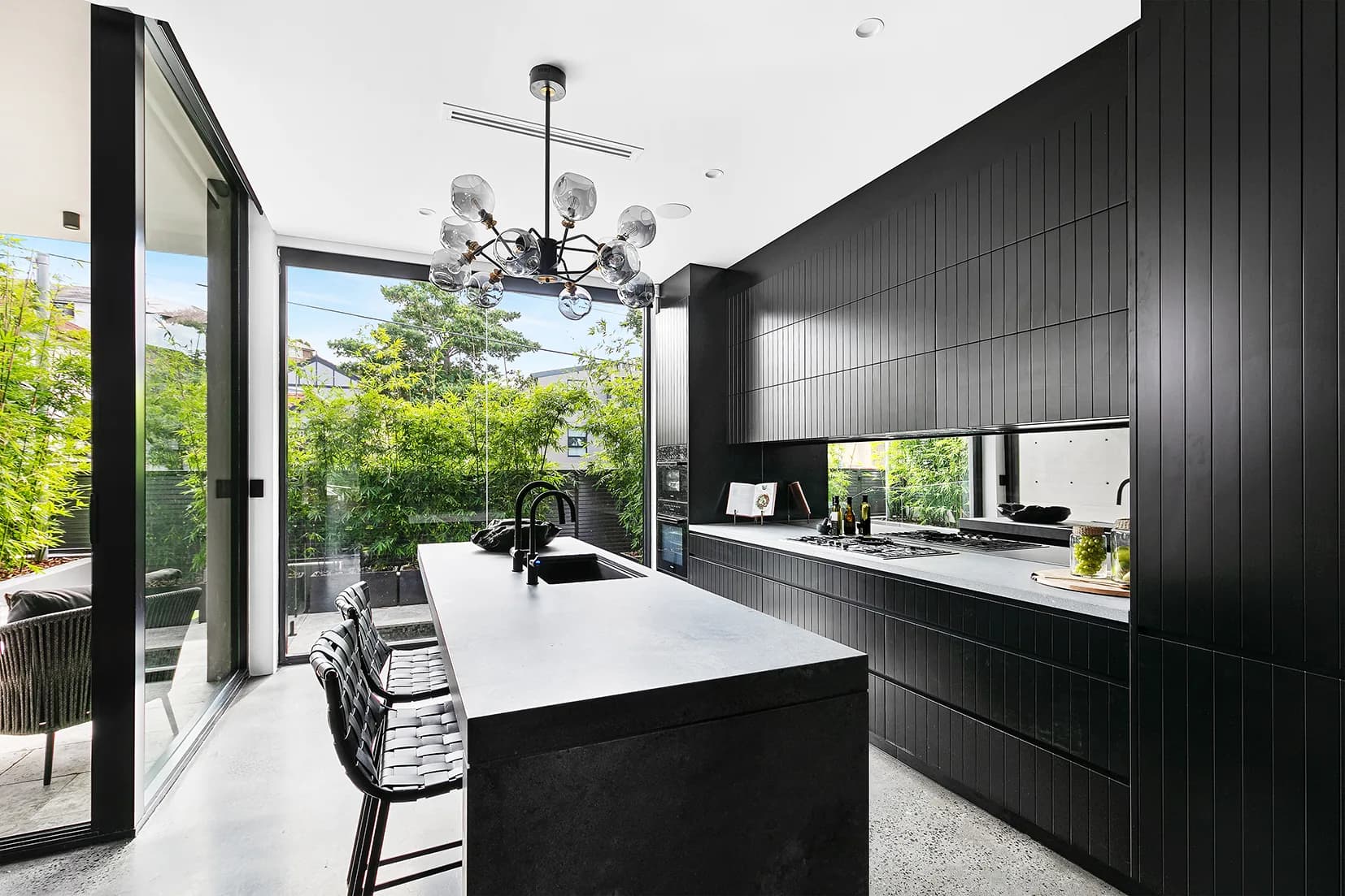 Entertainer's kitchen at The Arc in Black Tempal stone with black joinery and a long island bench