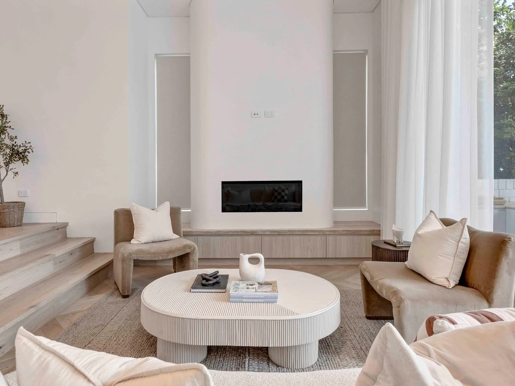 Stepped living room at Hillary with a Rinnai fireplace, herringbone oak floors and cream lounge
