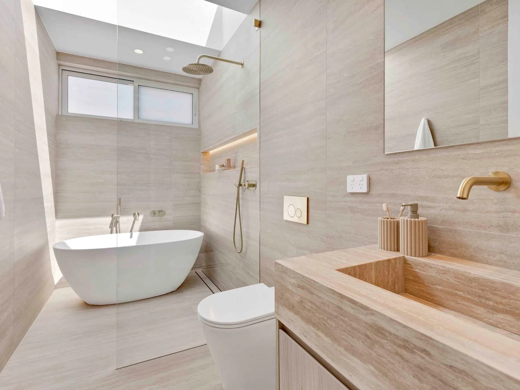 Main bathroom at Hillary with a freestanding bath, travertine-look tiling and a skylight