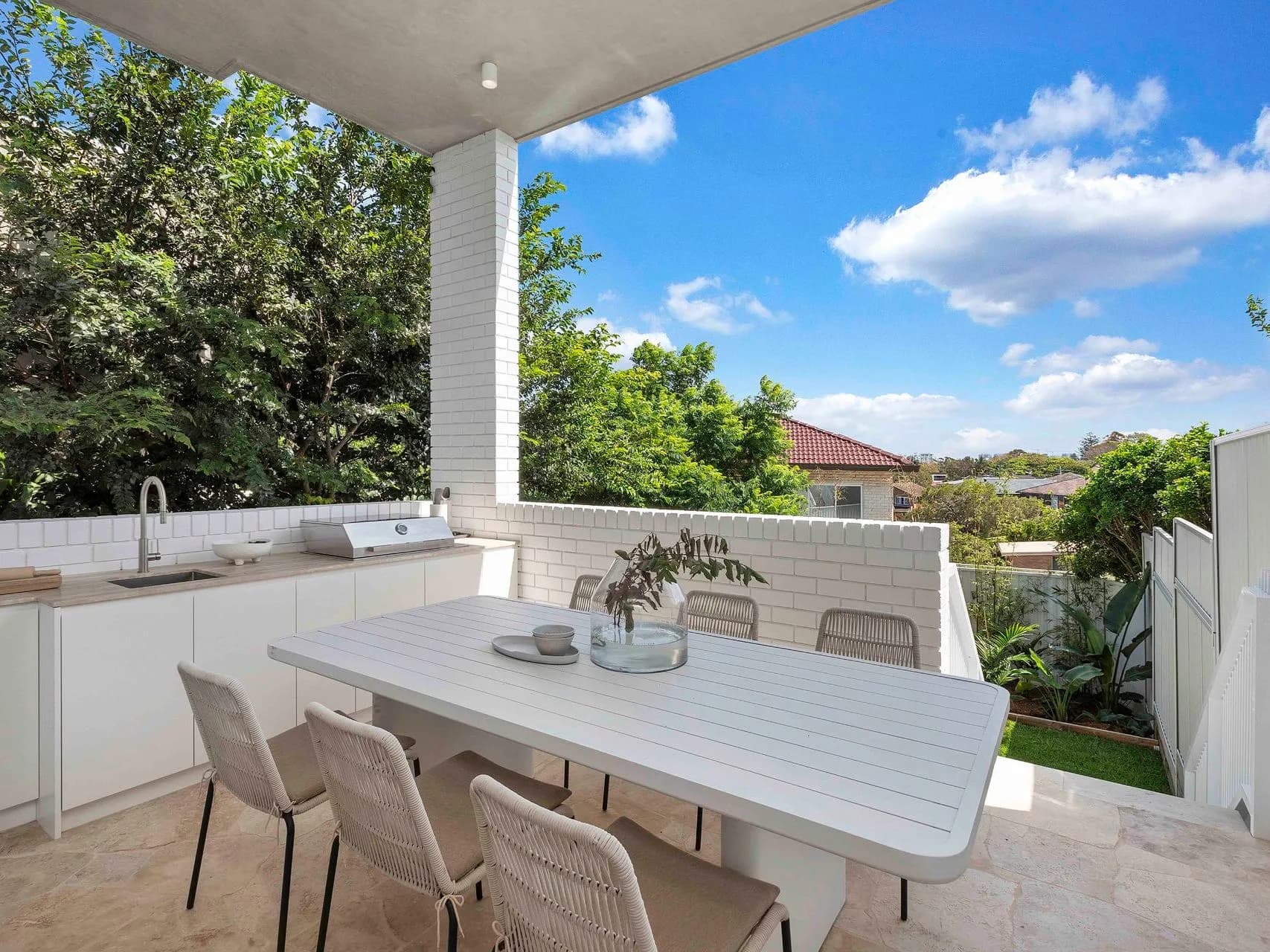 Covered alfresco at Hillary with an outdoor kitchen and dining overlooking the landscaped garden